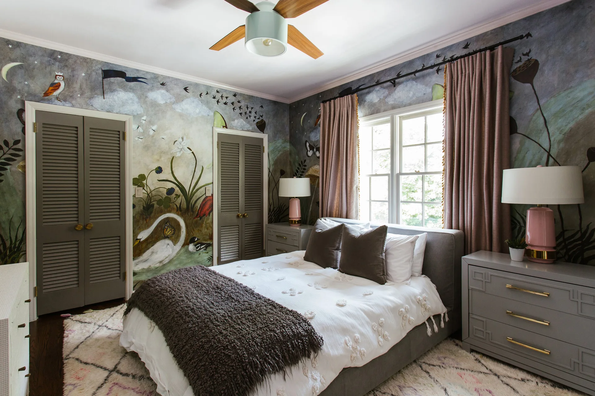 A children's bedroom features a detailed swan wall mural, gray louvered closet doors, and an upholstered bed flanked by gray nightstands.