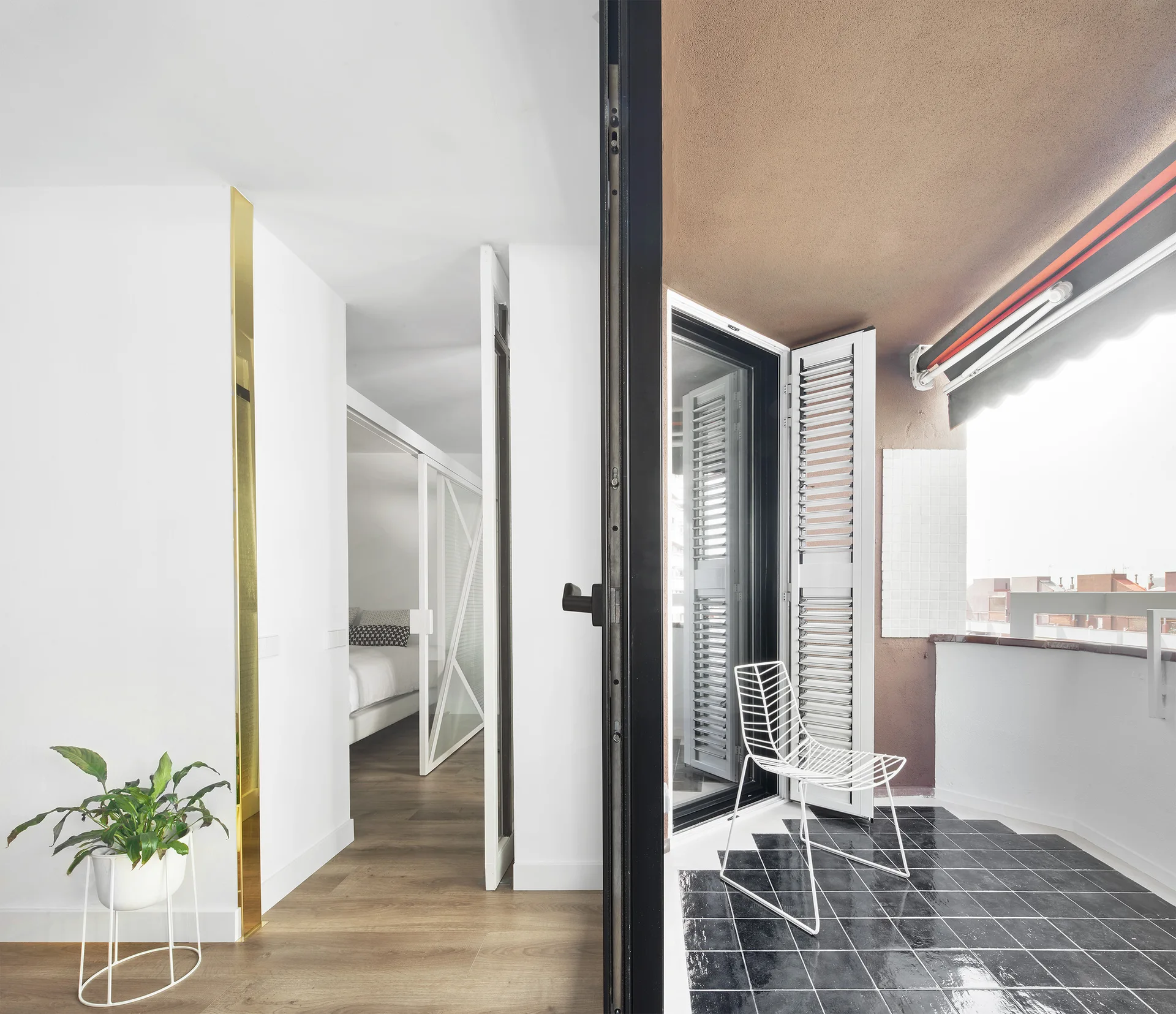 A split view of a bright hallway with wood flooring and an adjoining balcony featuring glossy black floor tiles and a white wire chair.