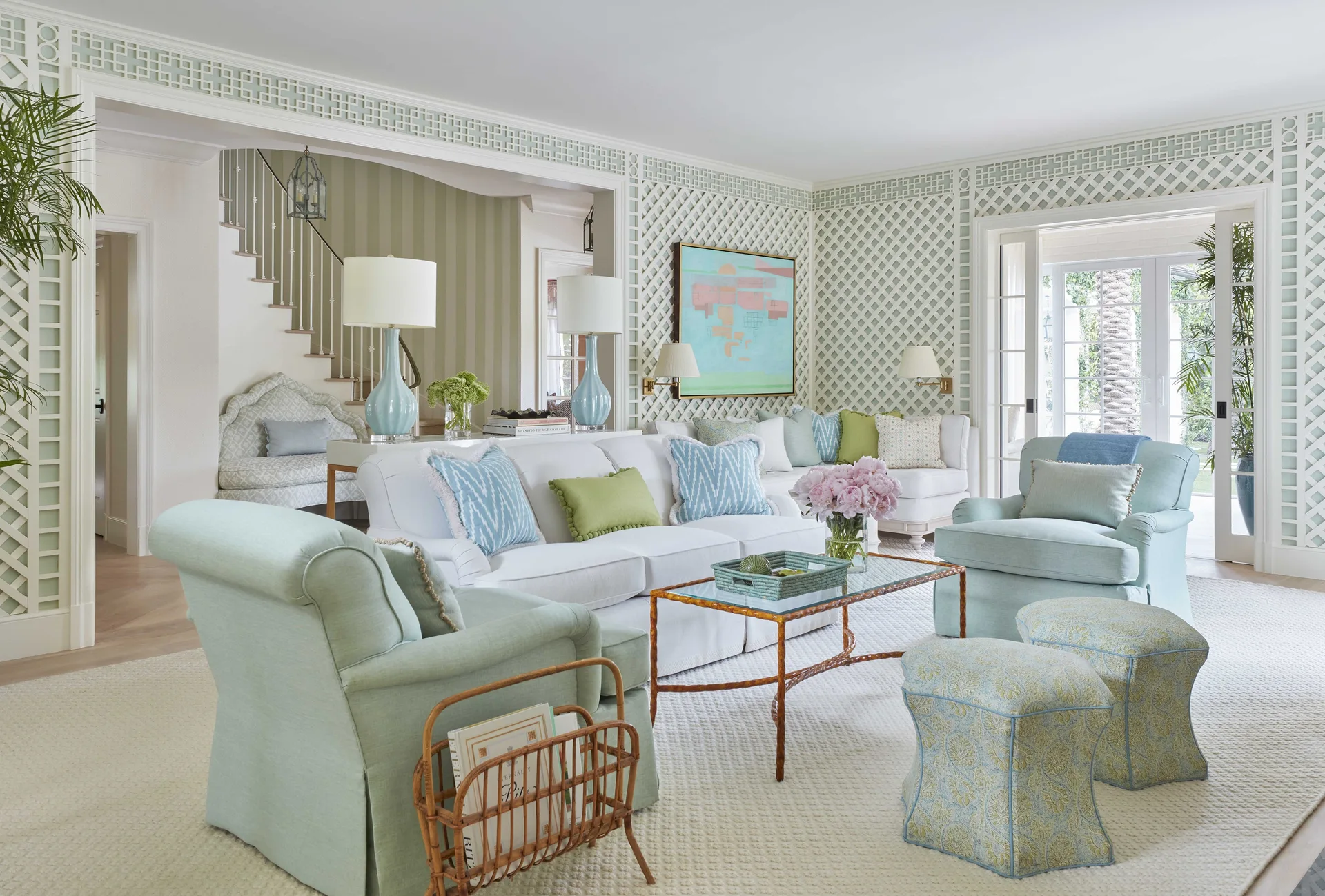 A bright living room features a white sofa, pale blue armchairs, and decorative white wood lattice paneling on the walls.