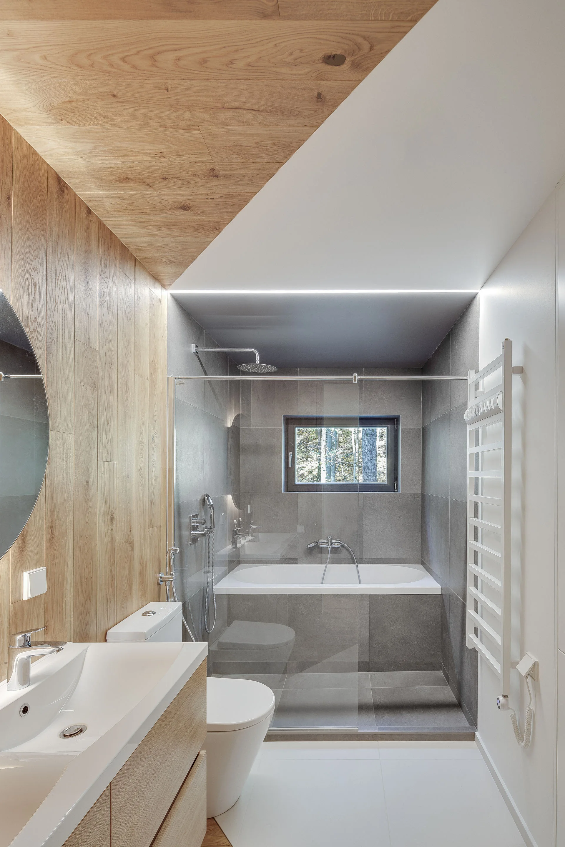 A modern bathroom featuring light wood wall paneling, a white sink vanity, and a gray-tiled shower alcove with an integrated bathtub.