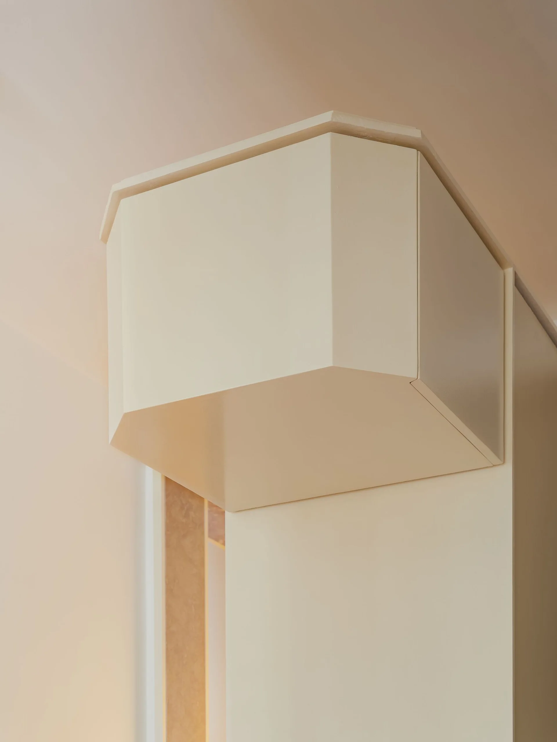 An off-white geometric architectural soffit with a matte finish projects from a smooth painted wall and ceiling.