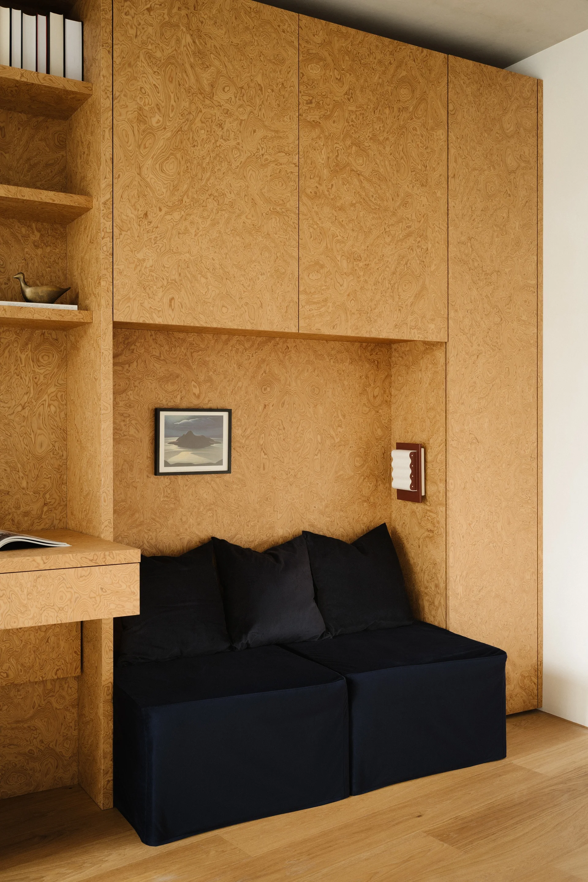 A custom burl wood veneer wall unit features built-in storage cabinets, open shelving, and an integrated black upholstered bench.