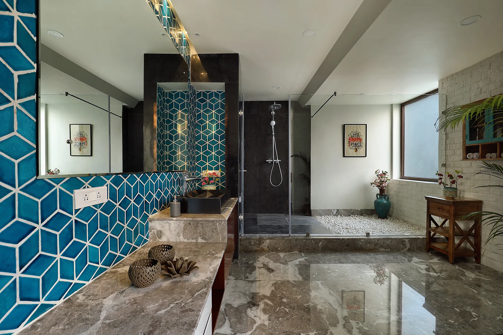 A spacious modern bathroom features a teal geometric tiled wall, a polished marble vanity, a glass walk-in shower, and glossy stone flooring.