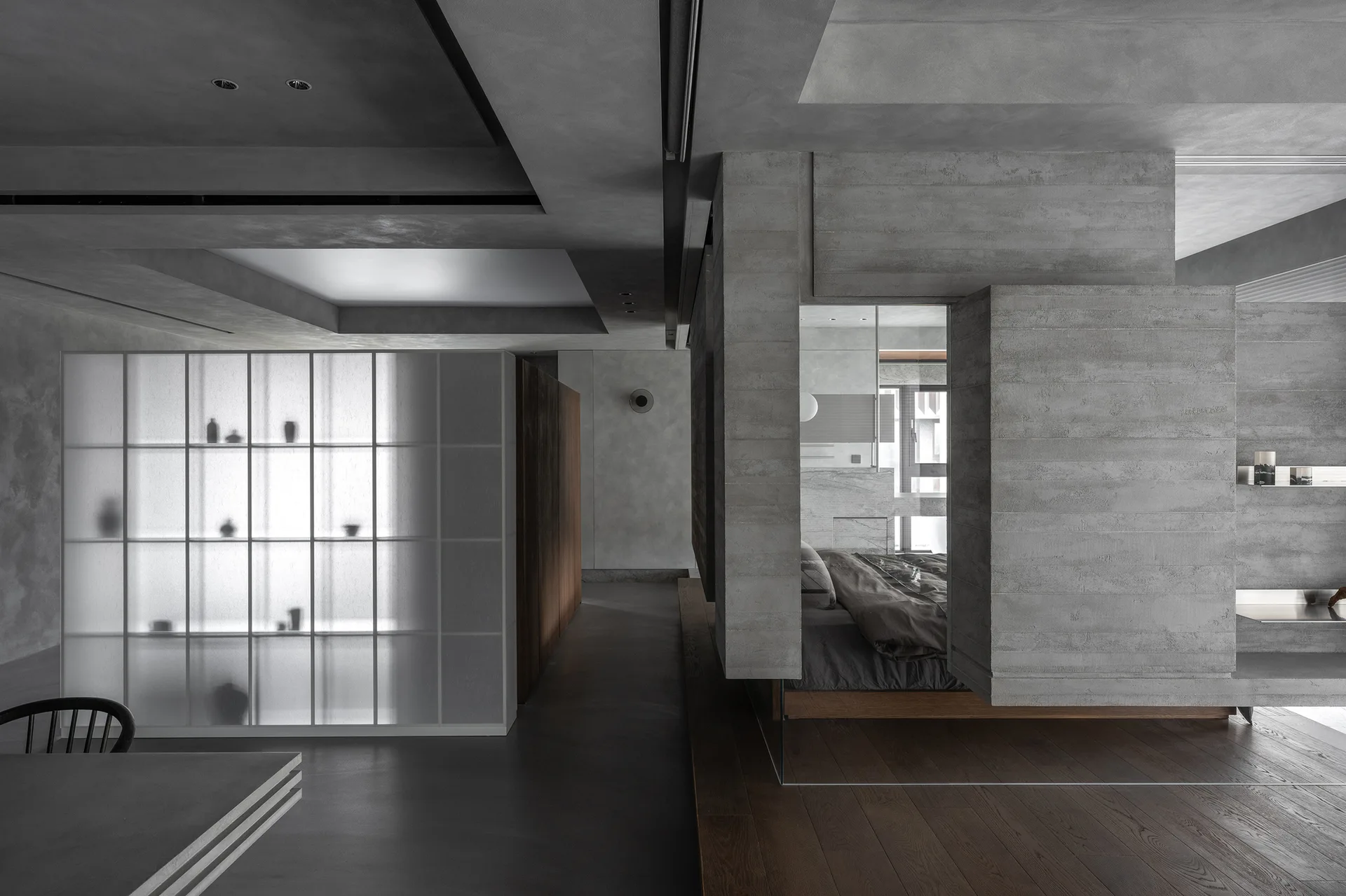 A minimalist bedroom is visible through a board-formed concrete architectural cutout, featuring dark wood flooring and a backlit frosted glass storage unit.