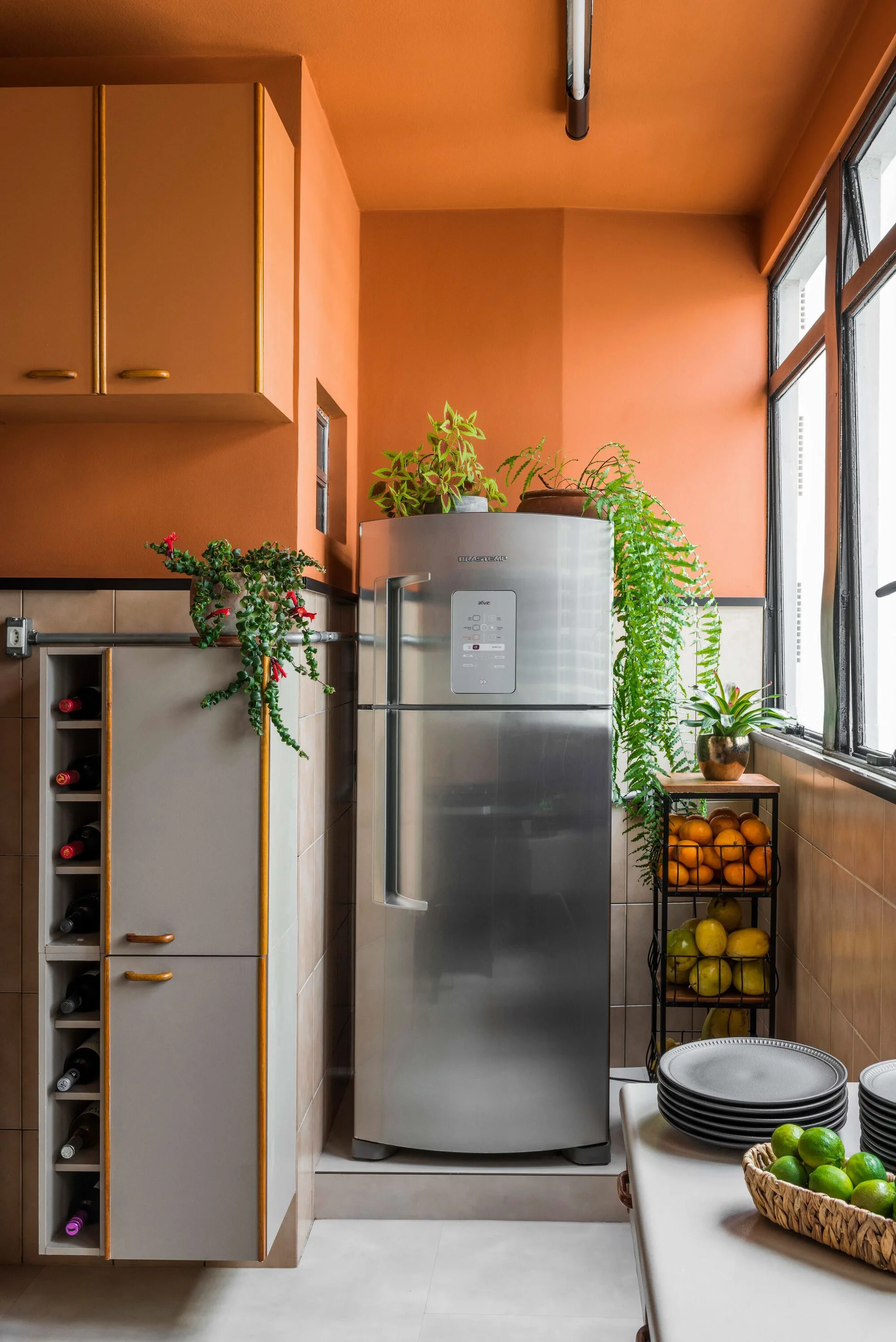 A kitchen corner features terracotta walls and ceiling, a stainless steel refrigerator, and a built-in gray cabinet with an integrated wine rack.