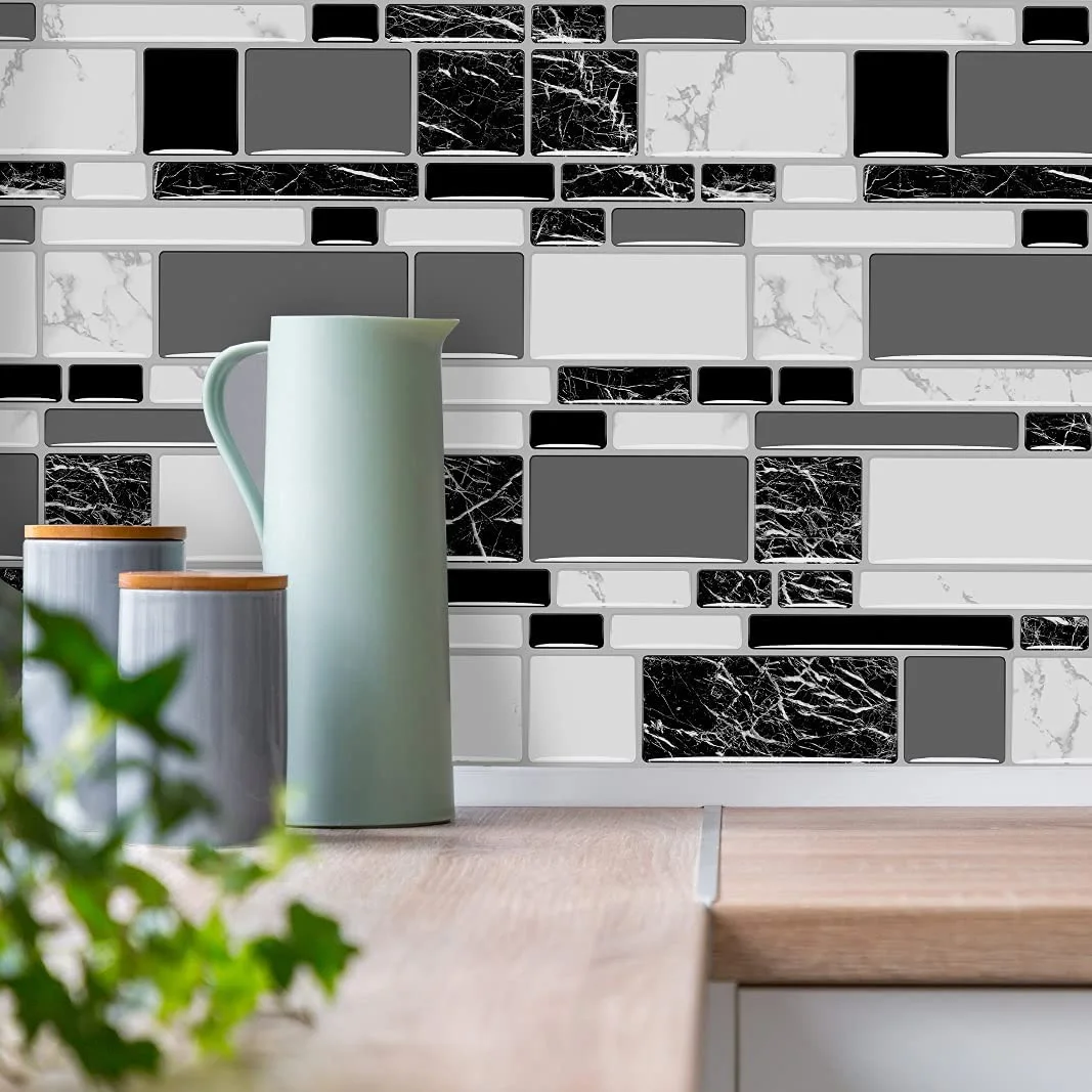 A glossy black, white, and gray geometric tile backsplash sits behind a wooden countertop holding a light green pitcher and gray canisters.