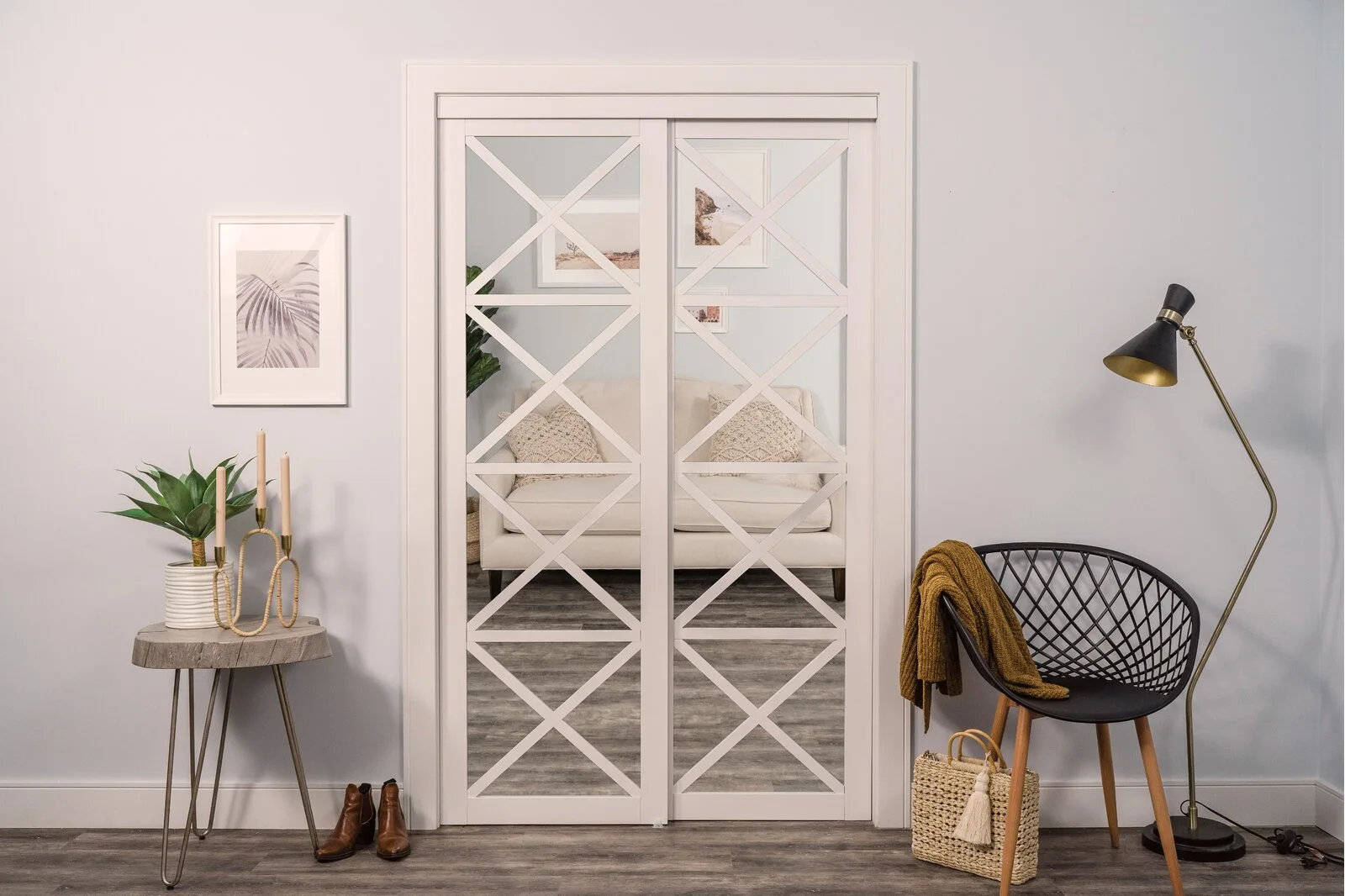 White mirrored sliding doors with a diamond geometric overlay stand between a hairpin leg side table and a black wire accent chair.