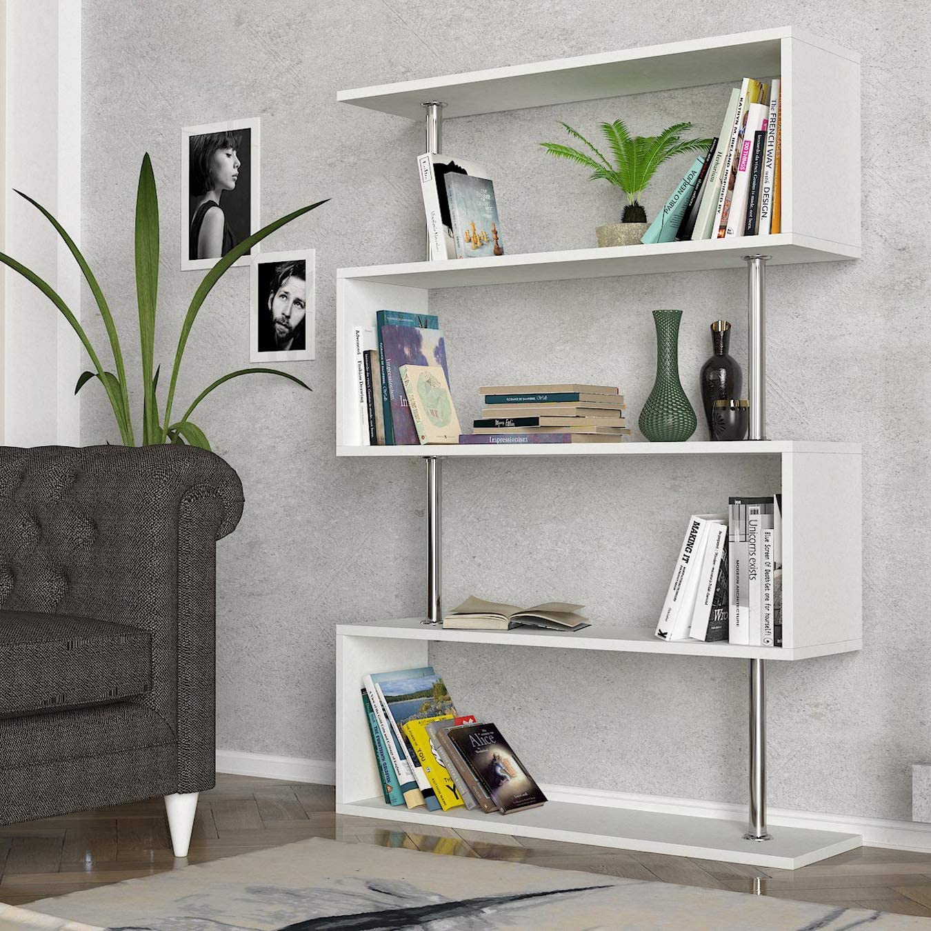 A white zigzag open shelving unit holding books and decorative items stands on a herringbone floor beside a grey tufted armchair.