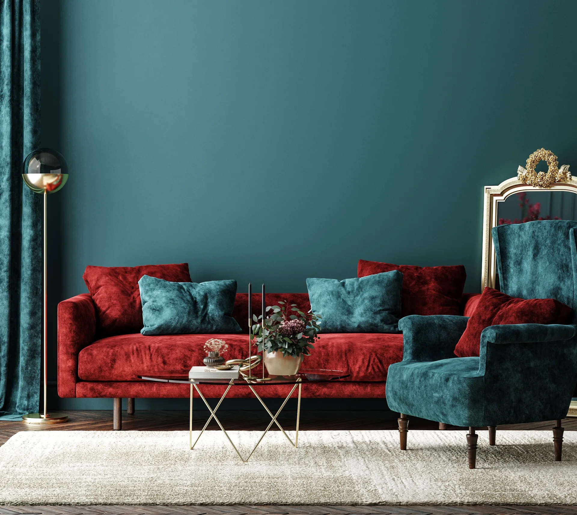 A teal living room features a bright red velvet sofa, a teal armchair, an ornate gold mirror, and a geometric glass coffee table on a light rug.