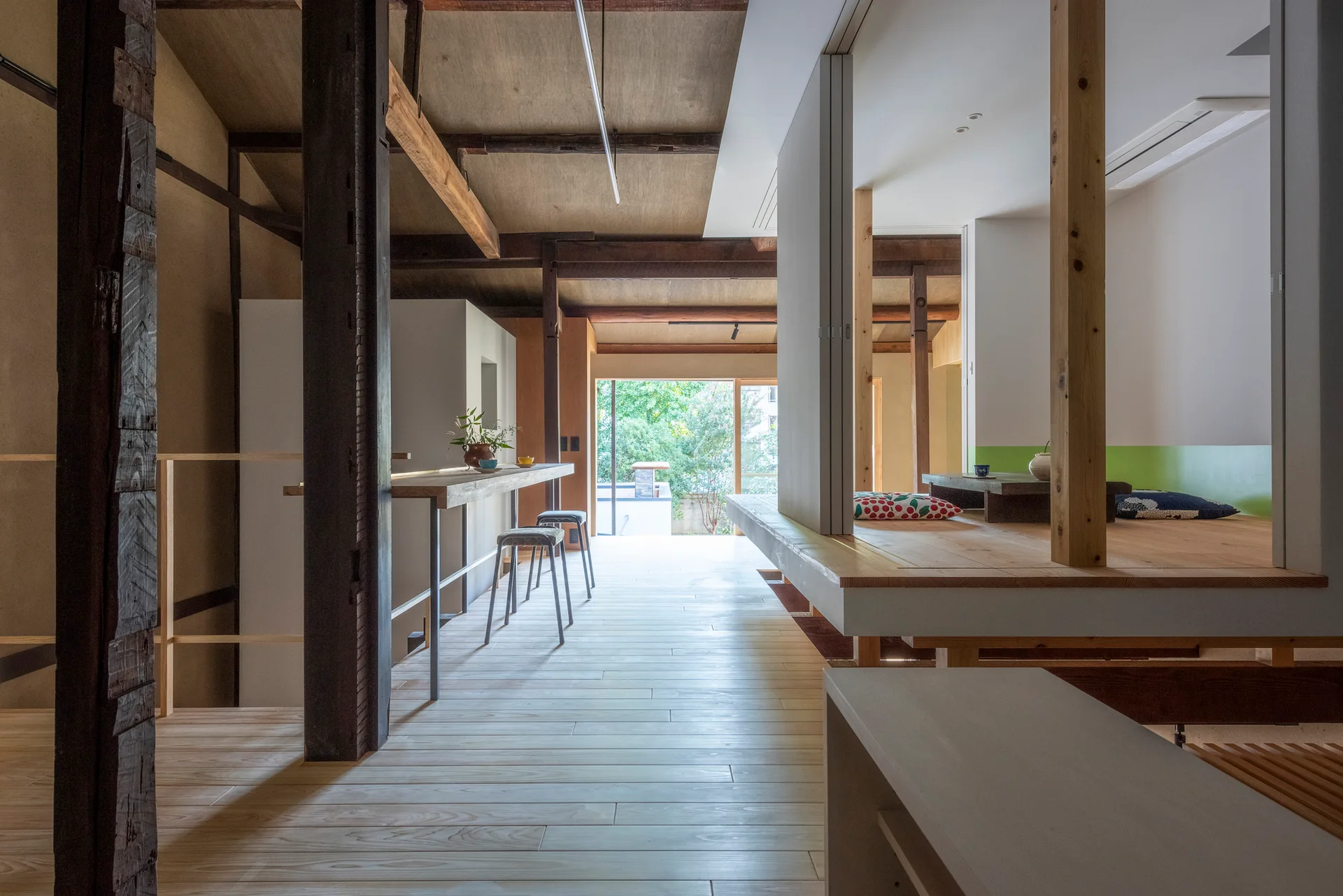A Japanese-style interior features a light wood floor hallway, a narrow breakfast bar, and a raised platform room with floor cushions.
