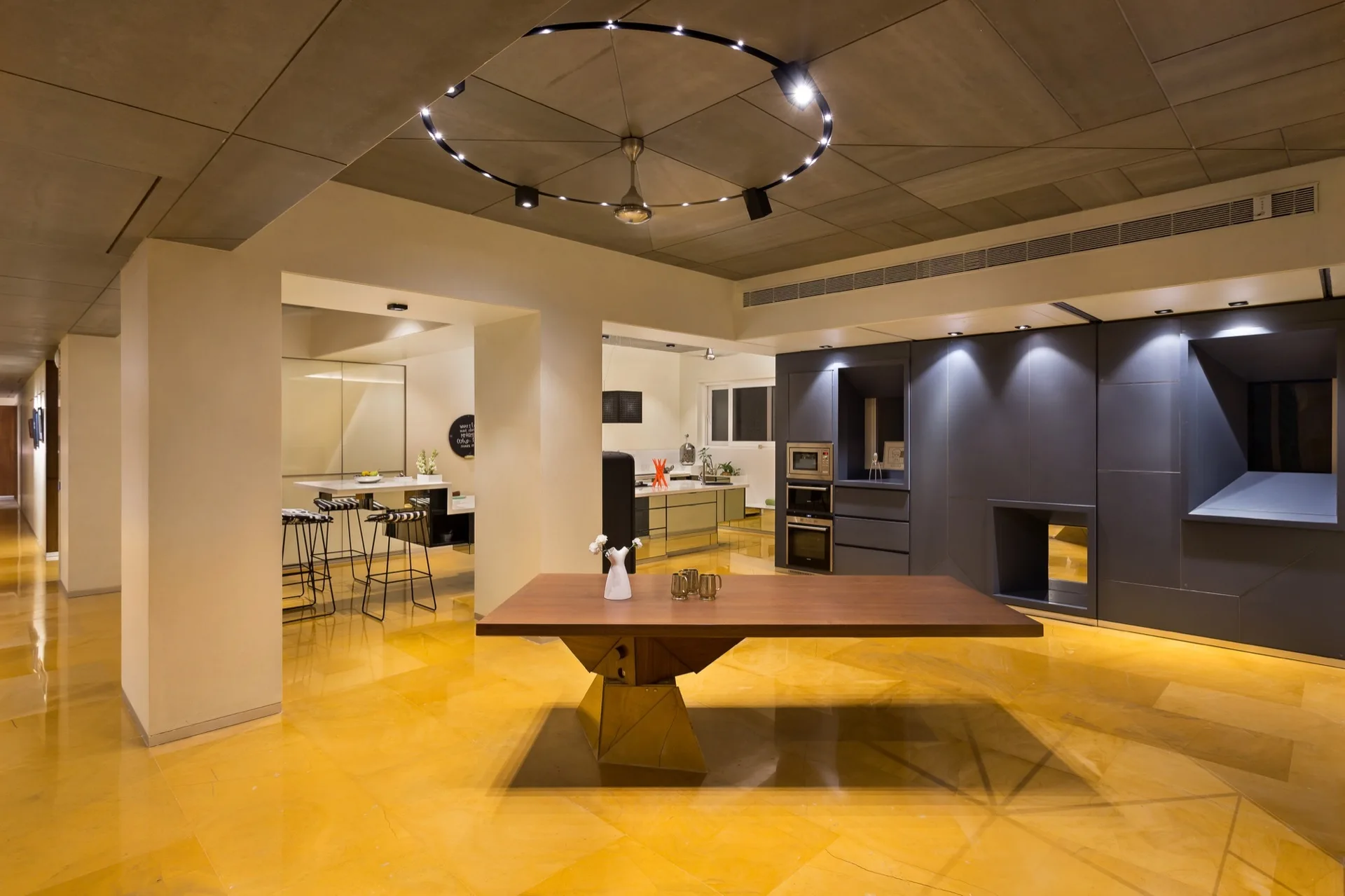 A spacious kitchen and dining area with highly polished yellow flooring, a dark wood dining table, and integrated gray cabinetry.
