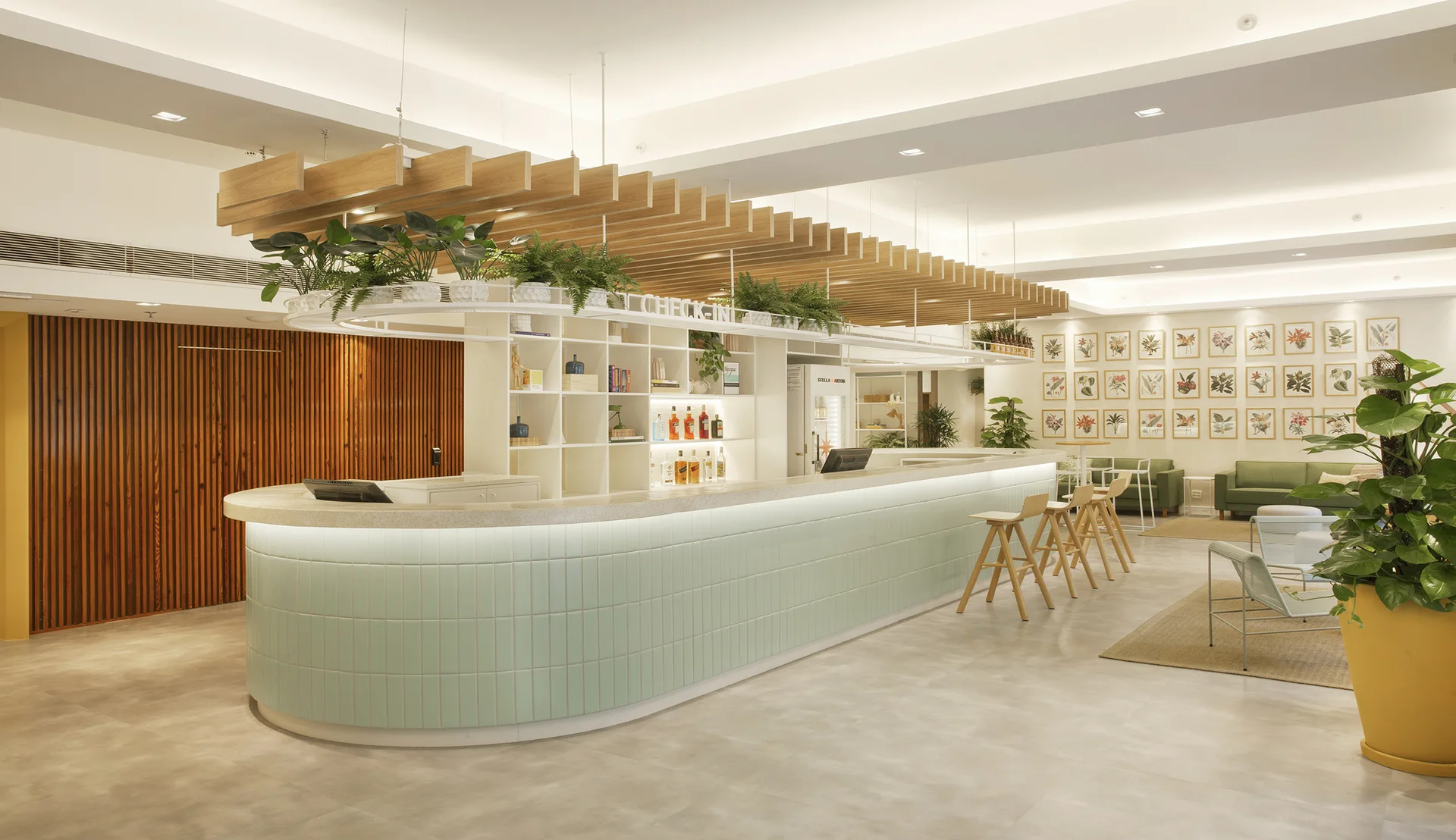 A spacious lobby featuring a curved mint green tiled reception desk underneath a slatted wood ceiling baffle decorated with green plants.