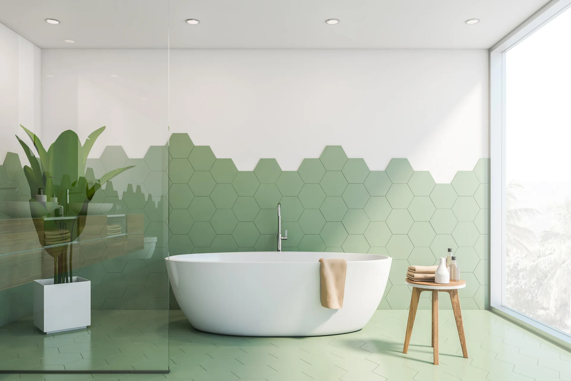 A modern bathroom features a white freestanding bathtub set against a wall with sage green hexagon tiles and a matching green chevron tiled floor.