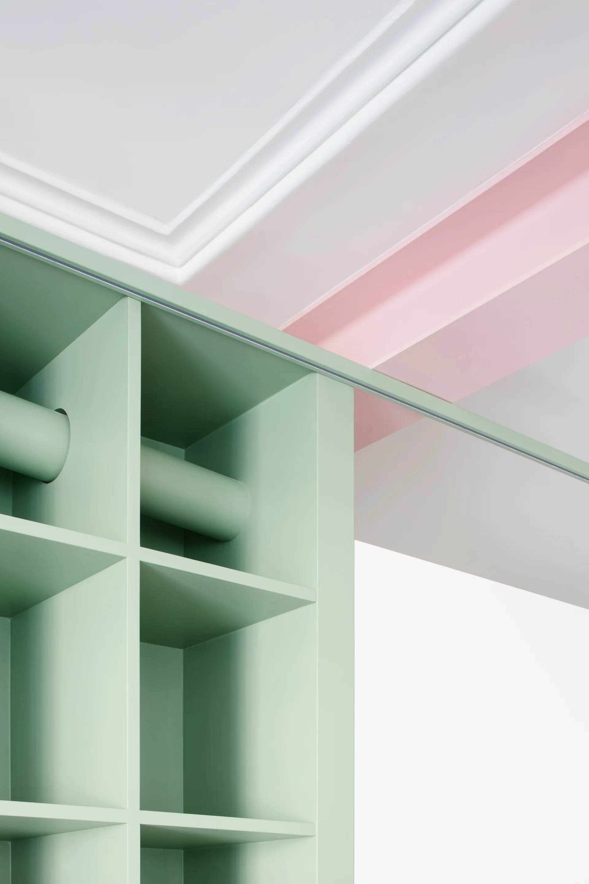 Close-up of a custom sage green grid shelving unit meeting a pale pink ceiling beam and white crown molding.