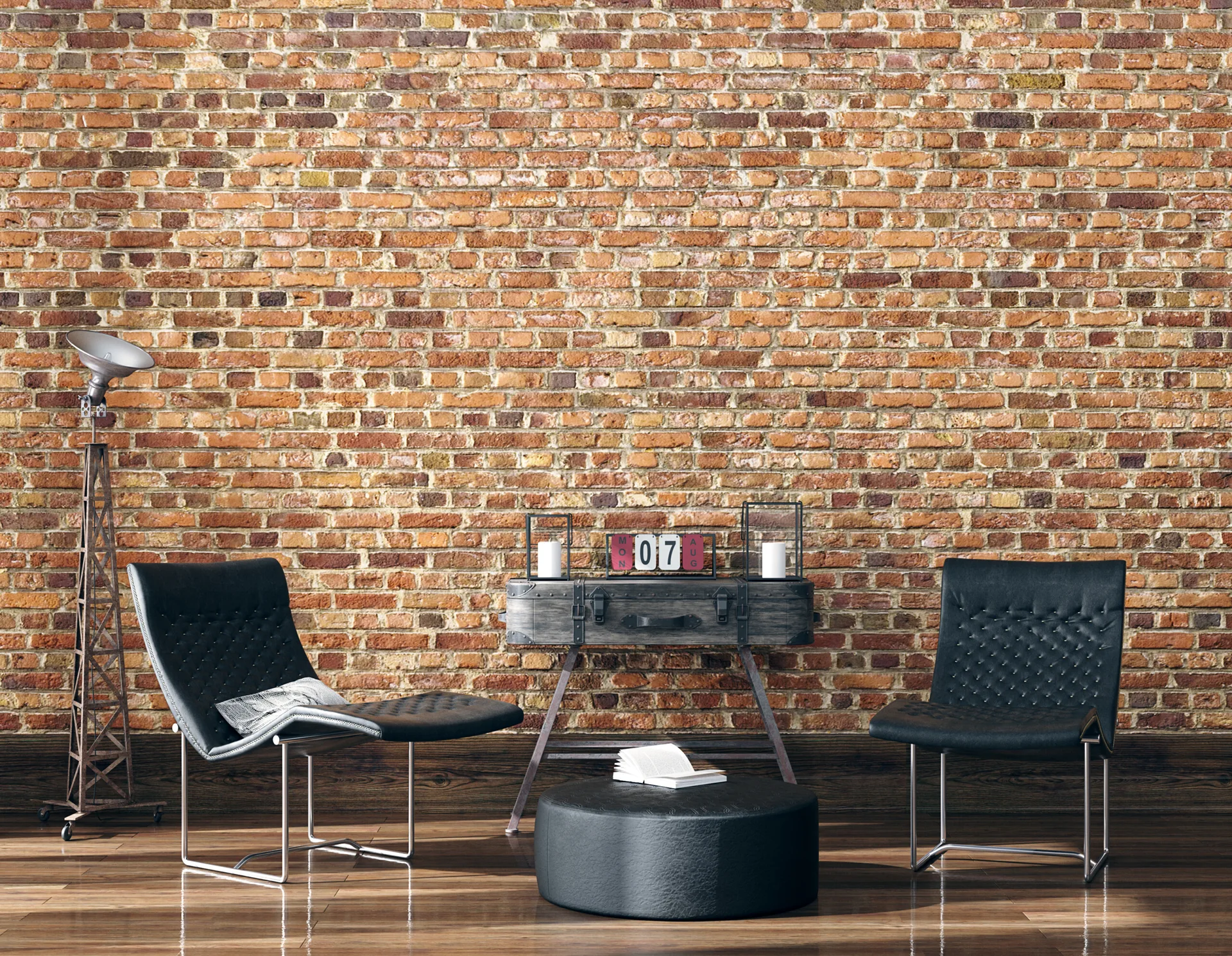 Two black leather armchairs and a round ottoman on dark hardwood floors in front of a rustic exposed brick wall with a vintage chest console.