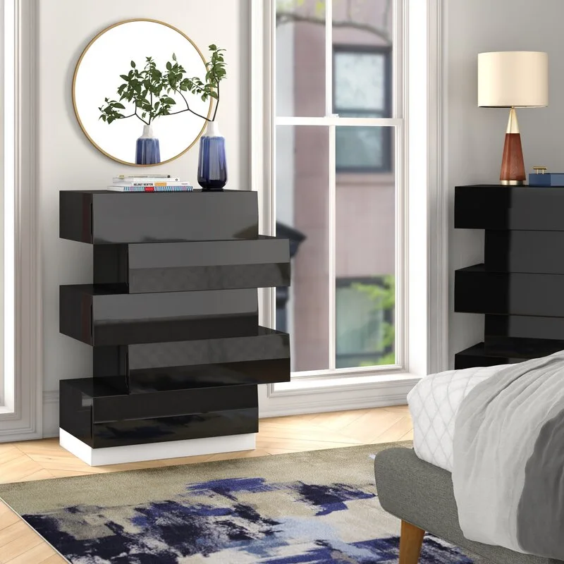 A bedroom corner features a modern high-gloss black dresser with a tiered geometric design next to a window and a round mirror.