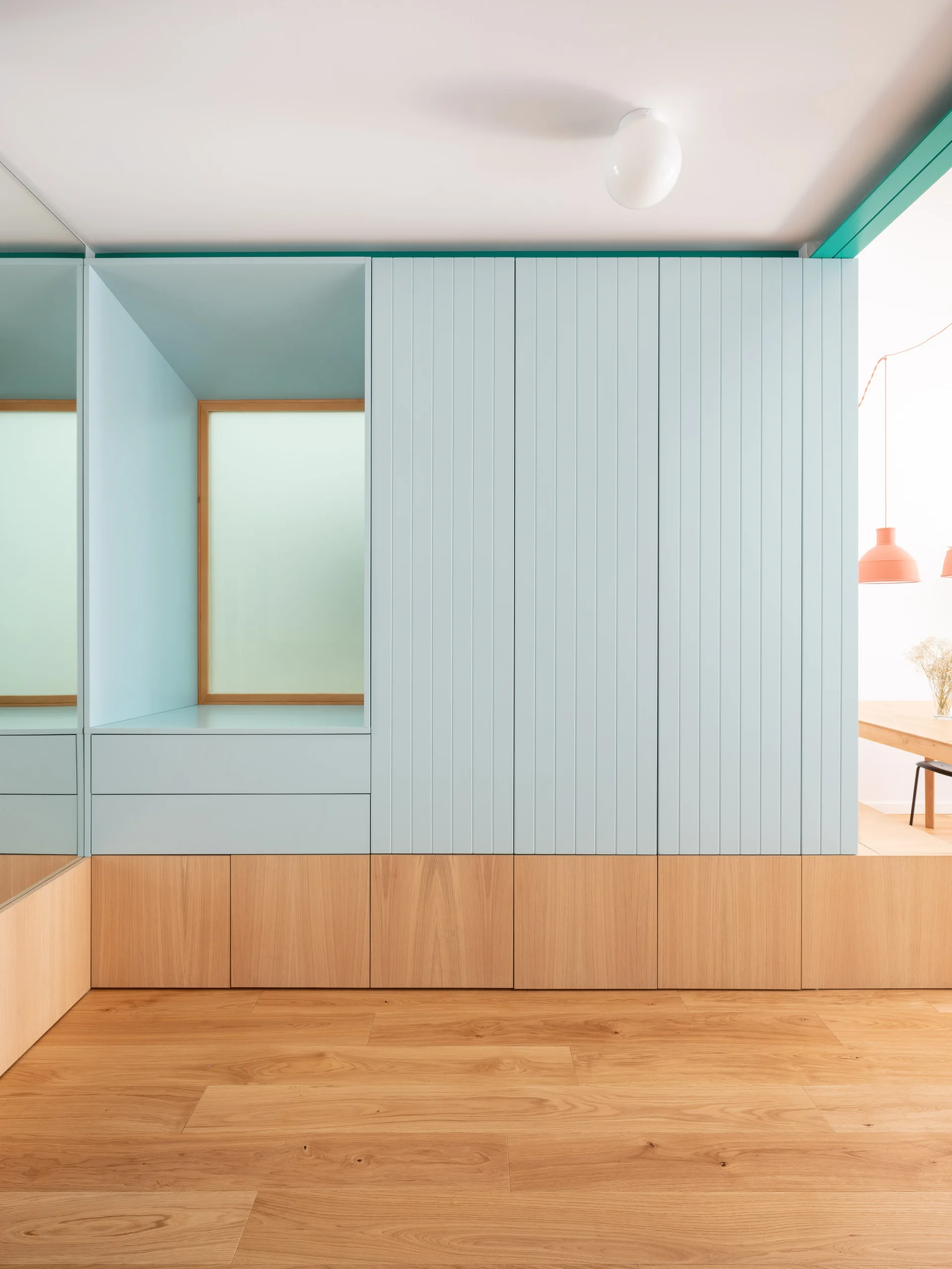 A built-in wall unit featuring vertical pale blue paneling and a recessed niche above a light wood-grained lower cabinet base.