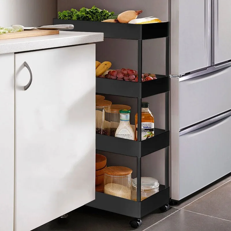 A slim black three-tier rolling cart filled with food items sits in the narrow gap between a white kitchen cabinet and a silver refrigerator.