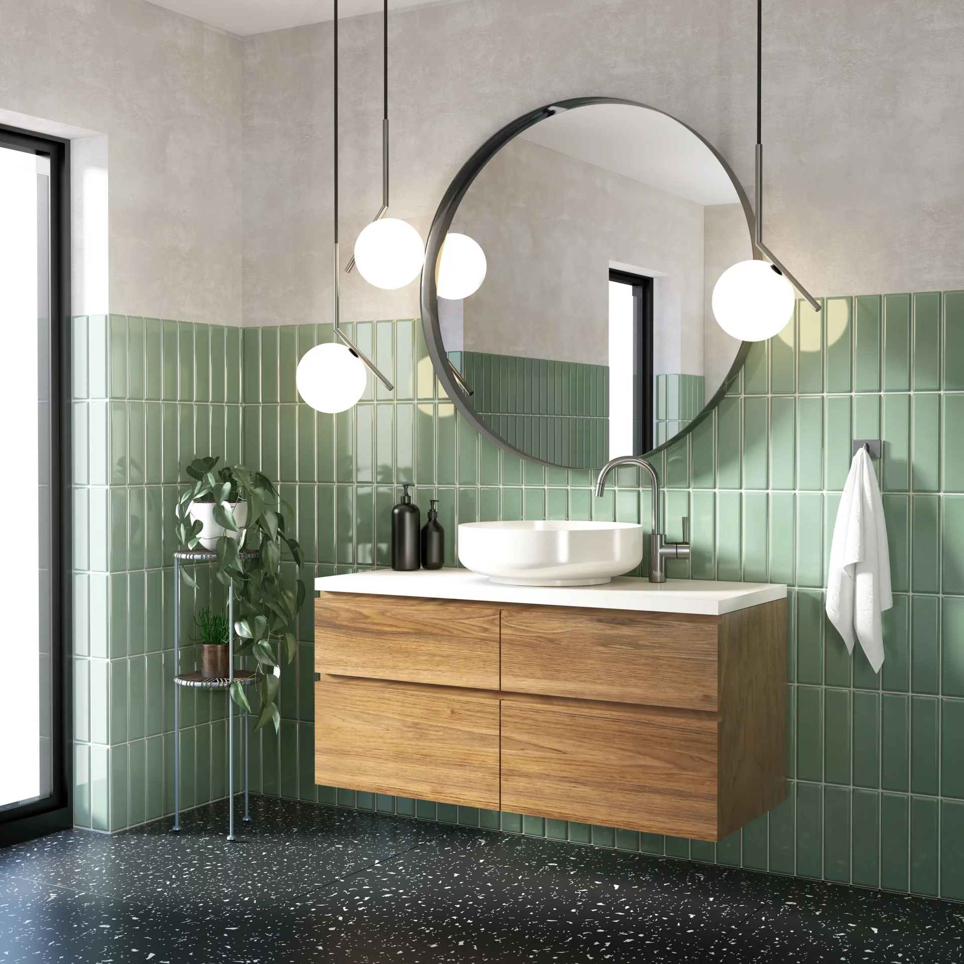 A floating wooden vanity with a round mirror and white vessel sink sits against sage green vertical tiles and a black speckled terrazzo floor.