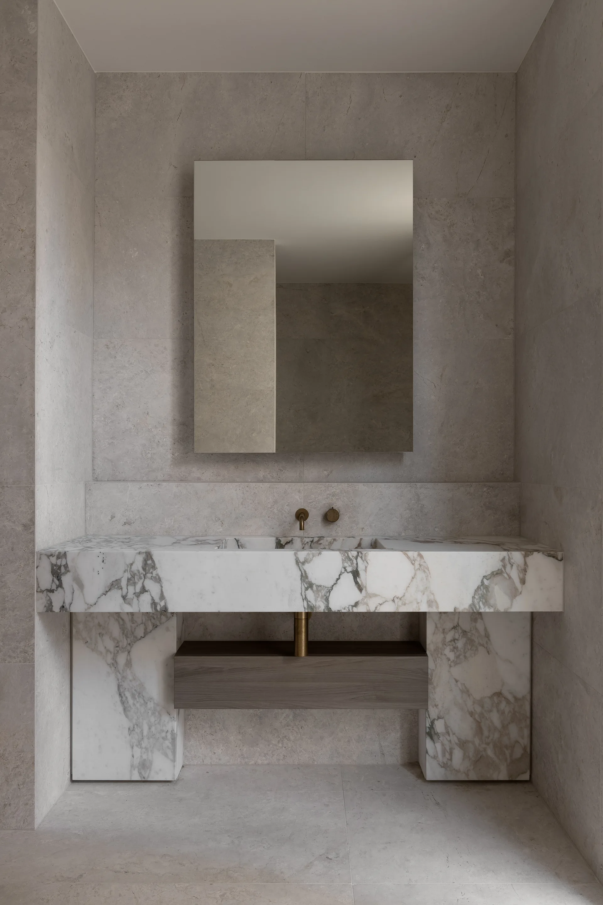A minimalist grey stone bathroom features a veined white marble vanity with an integrated sink and a rectangular frameless mirror.