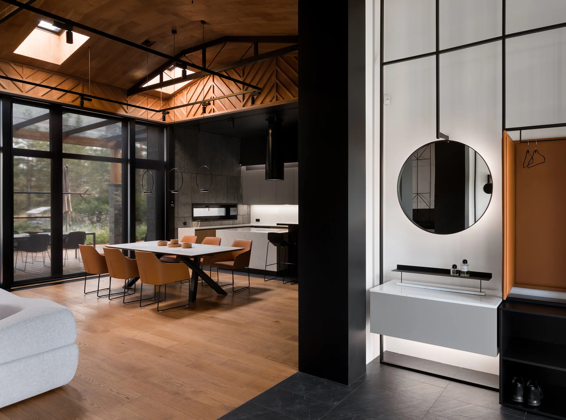 A modern open-plan dining room with a sloped wood ceiling, leather-upholstered chairs, and a black-framed entryway partition with a backlit mirror.