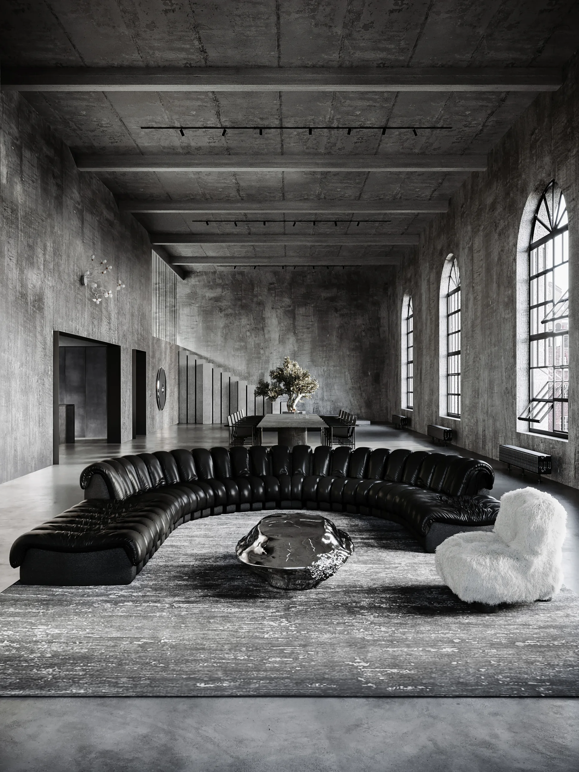 A spacious concrete loft features a large curved black leather sofa, a textured rug, a metallic coffee table, and tall arched windows.