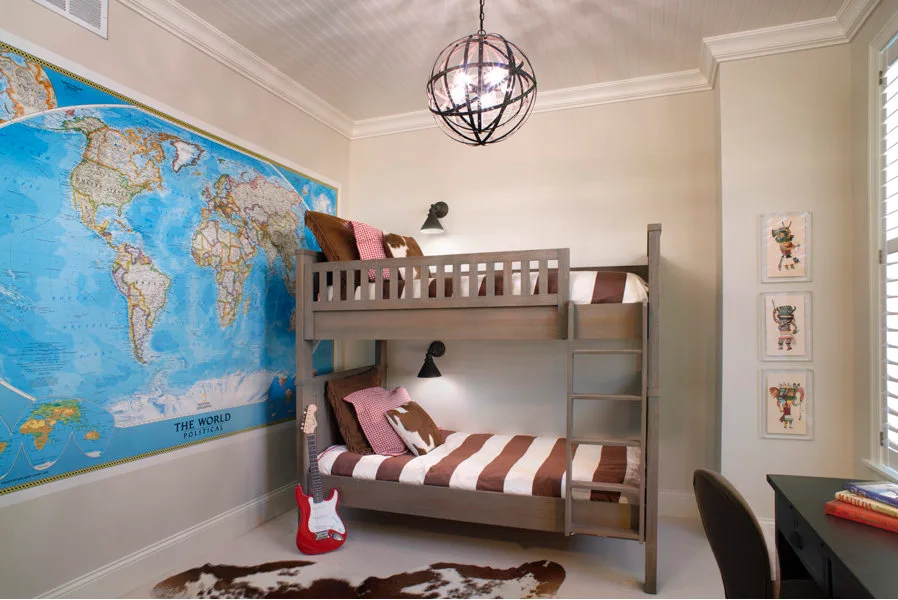 A children's bedroom features a grey wooden bunk bed set against a massive world map mural with a cowhide rug on the floor.