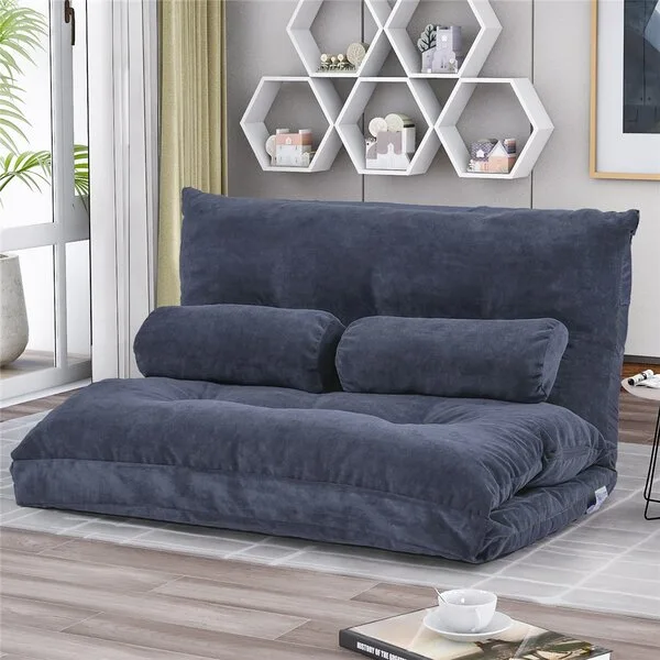 A plush dark blue foldable floor sofa sits on a patterned grey rug in front of white hexagonal wall shelves.