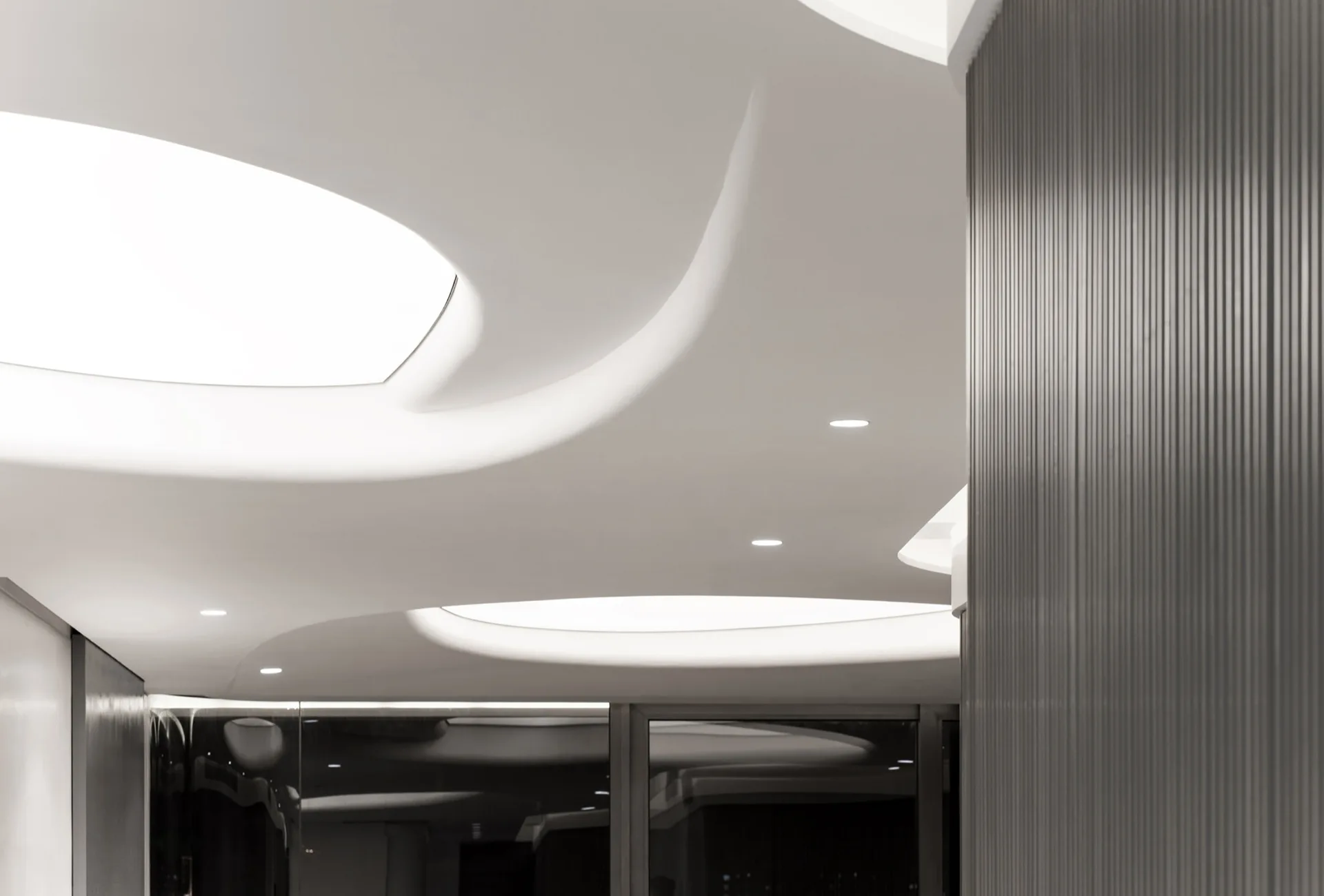 A modern white ceiling with organic curved recesses and integrated cove lighting next to a dark gray fluted wall panel.