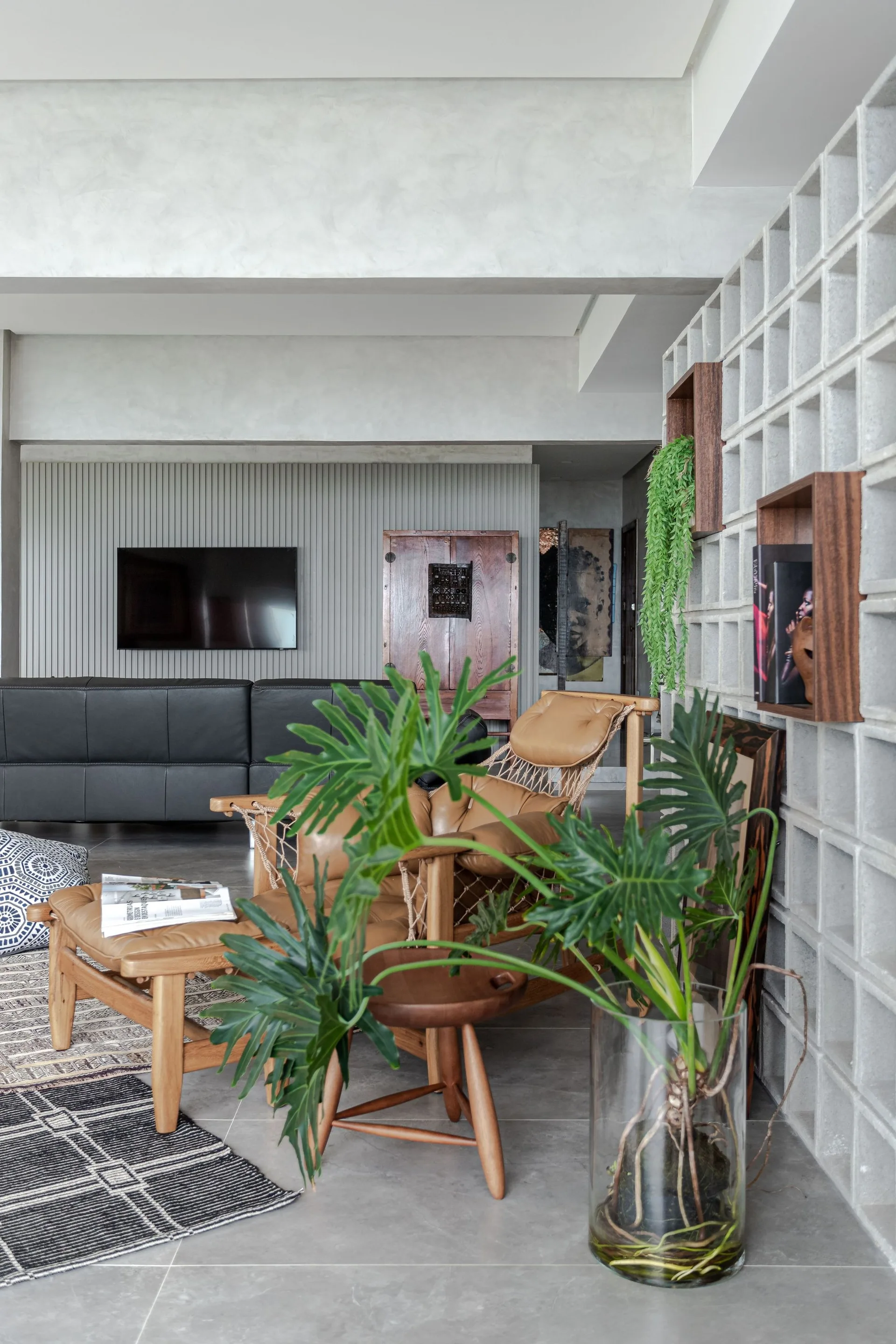 A contemporary living room featuring a concrete breeze block partition wall, a tan leather lounge chair, and a vertical slatted accent wall.