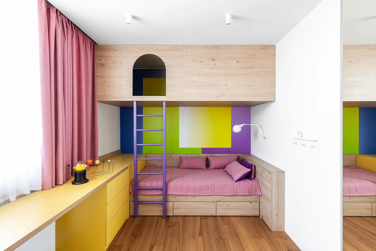 A children's bedroom featuring a built-in wood loft bed with a purple ladder, a yellow desk, and color-blocked walls.