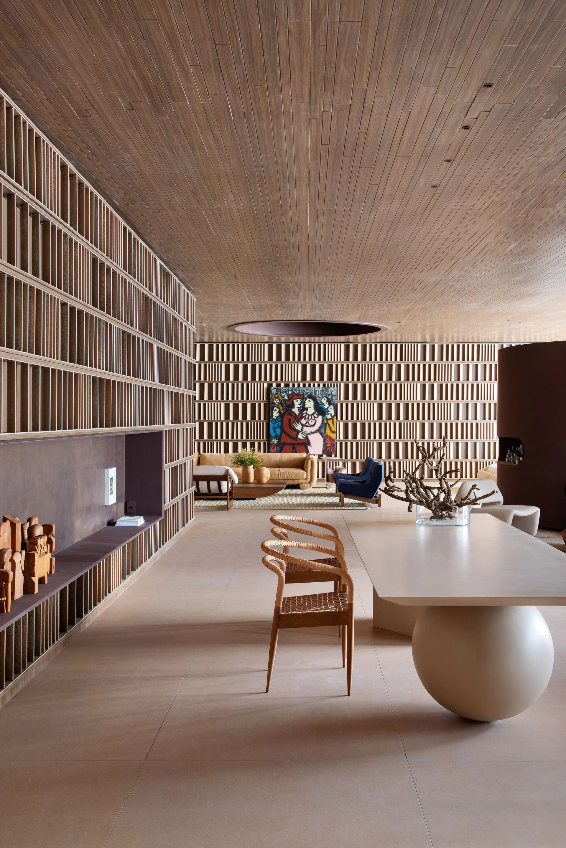 A spacious modern room with wood-plank ceilings, extensive wood-slatted grid shelving on the walls, and a dining table featuring a spherical base.