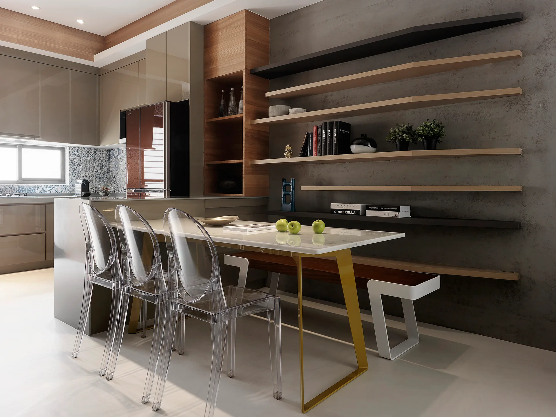 A modern marble dining table with gold legs paired with transparent acrylic chairs and a dark textured wall with floating wood shelves.